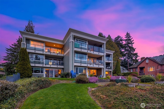 back of property at dusk with a lawn