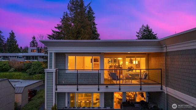 back of property at dusk with a balcony