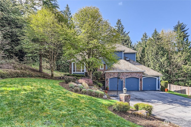 view of property hidden behind natural elements featuring fence, an attached garage, a front lawn, and driveway