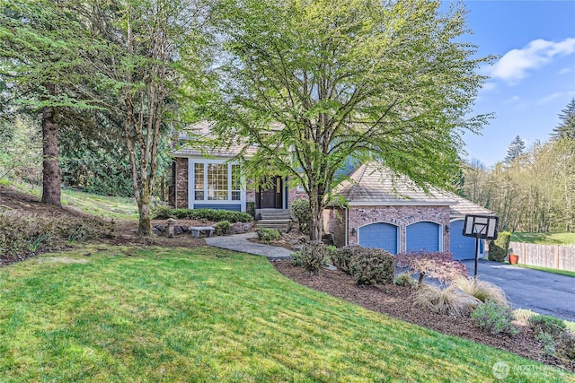 view of property hidden behind natural elements featuring driveway, fence, a front yard, a garage, and brick siding