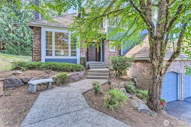 view of front of house featuring a chimney, brick siding, and a garage