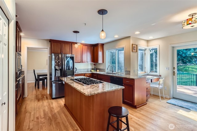 kitchen with stainless steel appliances, a sink, a center island, a peninsula, and light wood-style flooring