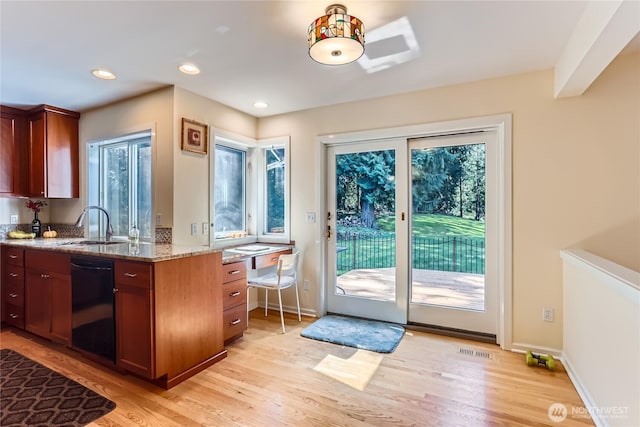 kitchen featuring light stone counters, a sink, light wood-style floors, dishwasher, and visible vents