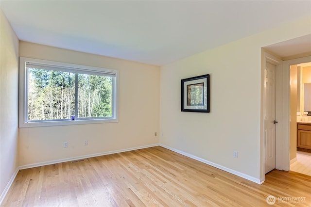 unfurnished room with baseboards, visible vents, and light wood-style floors