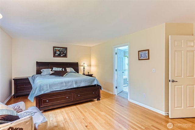 bedroom with connected bathroom, baseboards, and light wood-style flooring