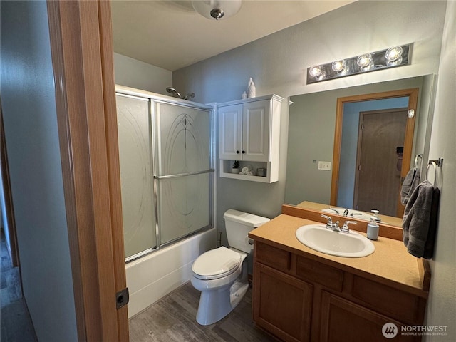full bathroom with toilet, combined bath / shower with glass door, wood finished floors, and vanity