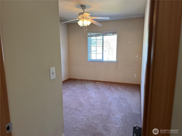 carpeted empty room featuring baseboards and a ceiling fan