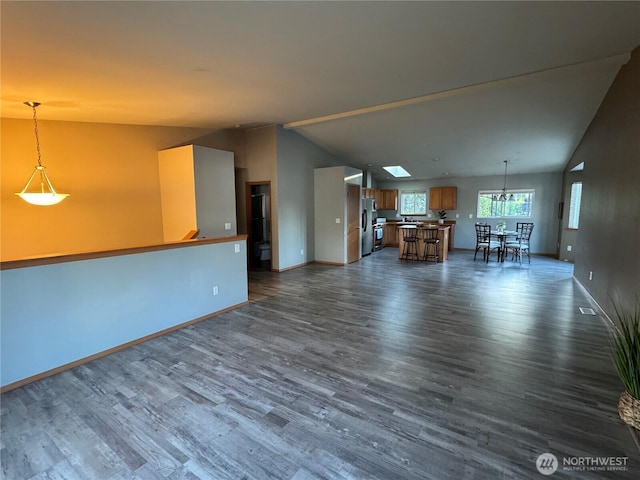 unfurnished living room featuring lofted ceiling, dark wood-style flooring, and baseboards