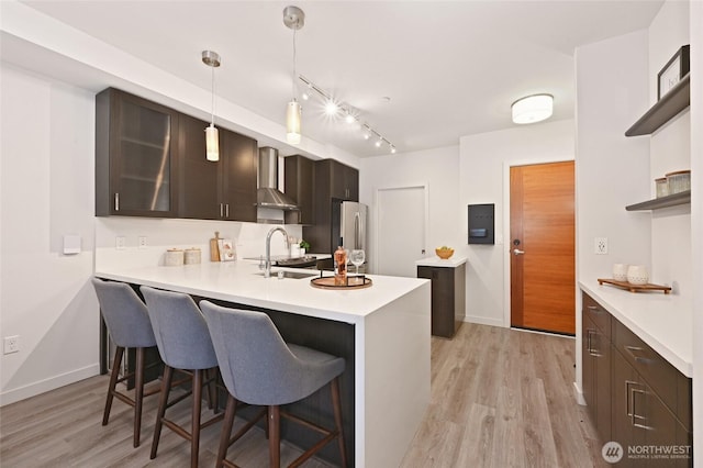 1760 NW 56th St Unit 601, Seattle, WA 98107 - kitchen featuring wall chimney exhaust hood, a sink, open shelves, light countertops, and a breakfast bar area