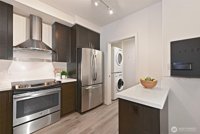 1760 NW 56th St Unit 601, Seattle, WA 98107 - kitchen with stacked washer and clothes dryer, light countertops, wall chimney range hood, and stainless steel appliances