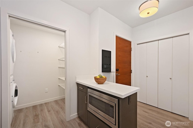 1760 NW 56th St Unit 601, Seattle, WA 98107 - kitchen featuring light wood-type flooring, light countertops, stacked washer / dryer, and stainless steel microwave