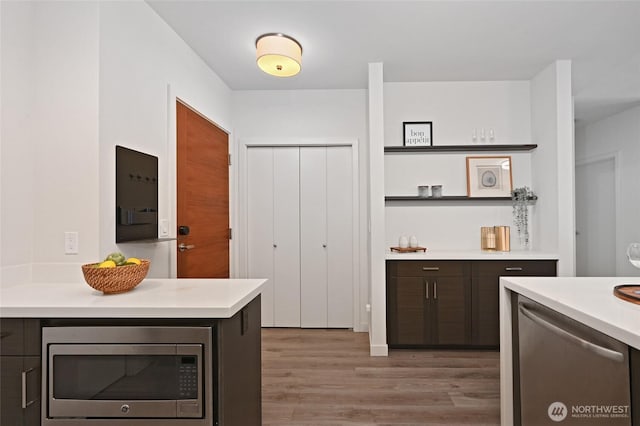 1760 NW 56th St Unit 601, Seattle, WA 98107 - kitchen featuring appliances with stainless steel finishes, dark brown cabinets, light wood-style floors, and light countertops