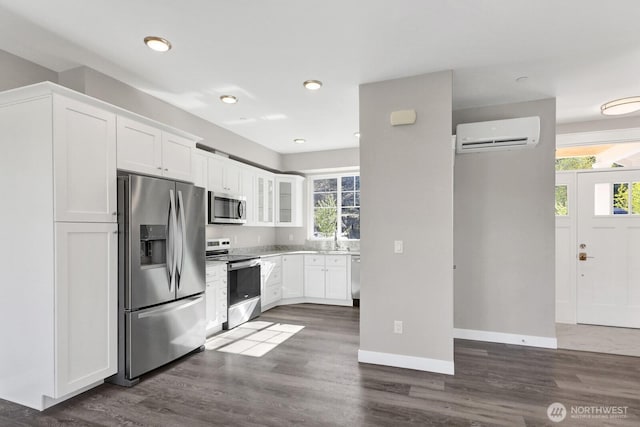 kitchen featuring white cabinets, baseboards, an AC wall unit, and appliances with stainless steel finishes