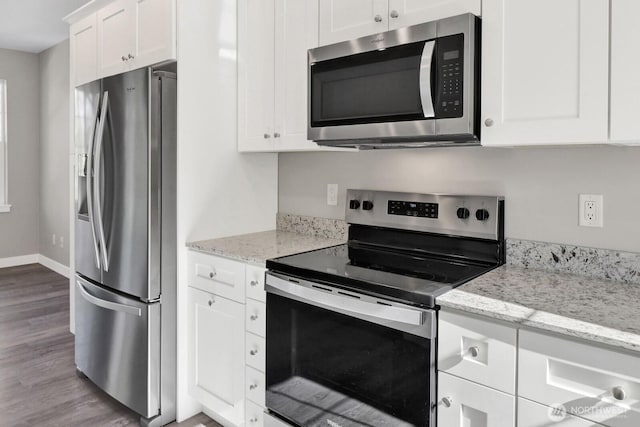 kitchen with light stone counters, wood finished floors, baseboards, appliances with stainless steel finishes, and white cabinetry