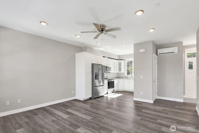 unfurnished living room with dark wood finished floors, a wall mounted air conditioner, baseboards, and ceiling fan