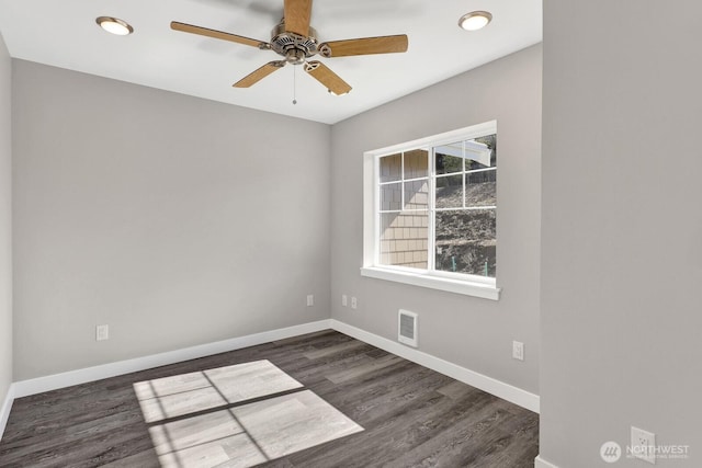 spare room featuring baseboards, visible vents, and dark wood finished floors