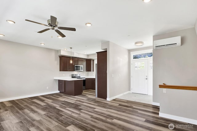 3513 Sussex Dr, Bellingham, WA 98226 - kitchen featuring an AC wall unit, dark brown cabinets, dark wood-style flooring, baseboards, and appliances with stainless steel finishes