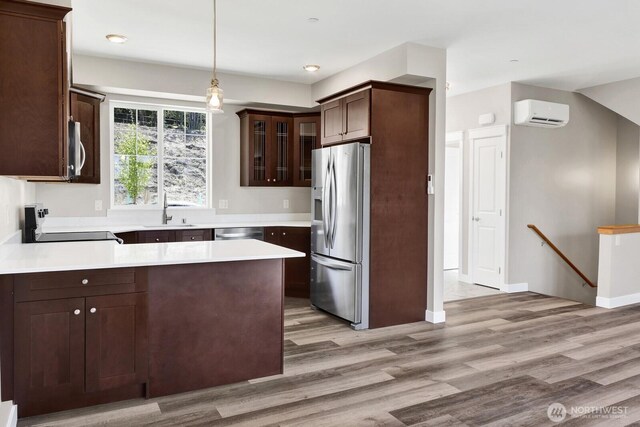 3513 Sussex Dr, Bellingham, WA 98226 - kitchen featuring a wall unit AC, dark brown cabinets, light wood finished floors, a peninsula, and appliances with stainless steel finishes