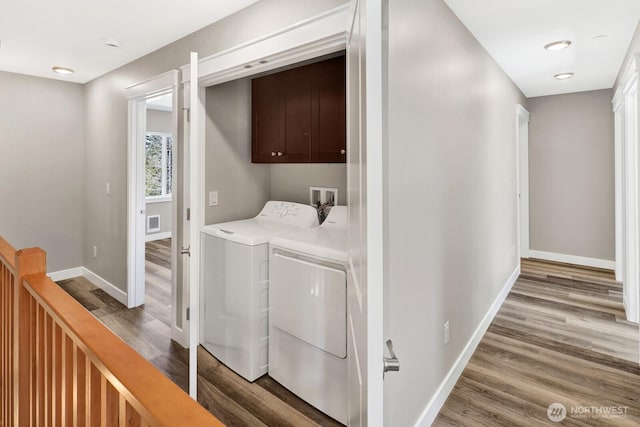 3513 Sussex Dr, Bellingham, WA 98226 - laundry room with wood finished floors, cabinet space, washing machine and clothes dryer, visible vents, and baseboards