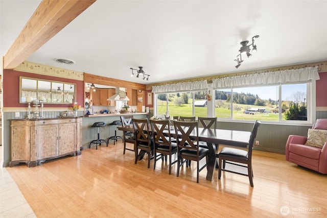 dining space featuring wainscoting, a healthy amount of sunlight, visible vents, and light wood-type flooring