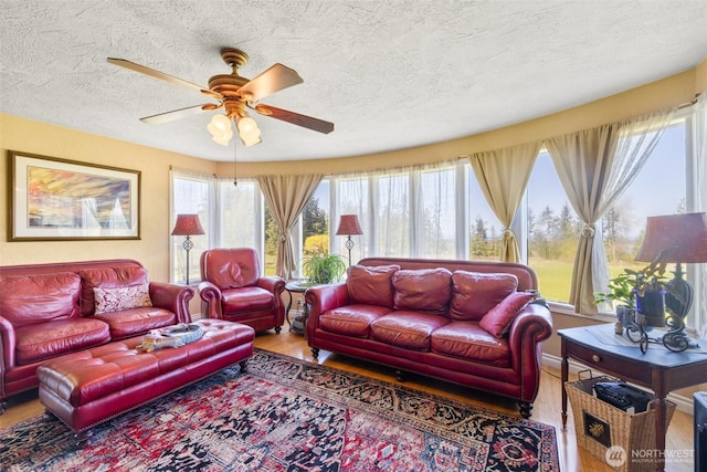 living room featuring wood finished floors, a textured ceiling, a ceiling fan, and a healthy amount of sunlight