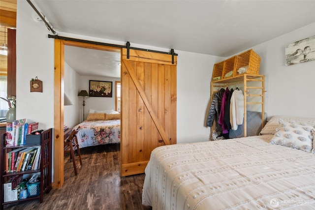 bedroom featuring a barn door, wood finished floors, and multiple windows