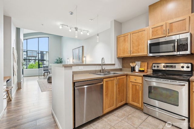 kitchen with light countertops, a sink, a peninsula, and stainless steel appliances