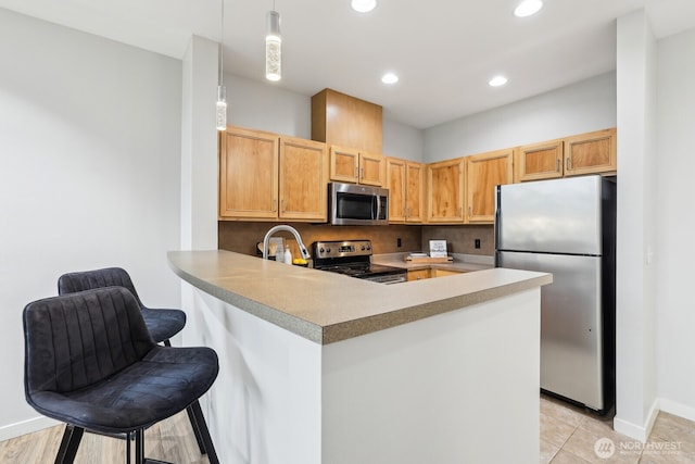 kitchen with appliances with stainless steel finishes, a peninsula, decorative light fixtures, baseboards, and recessed lighting