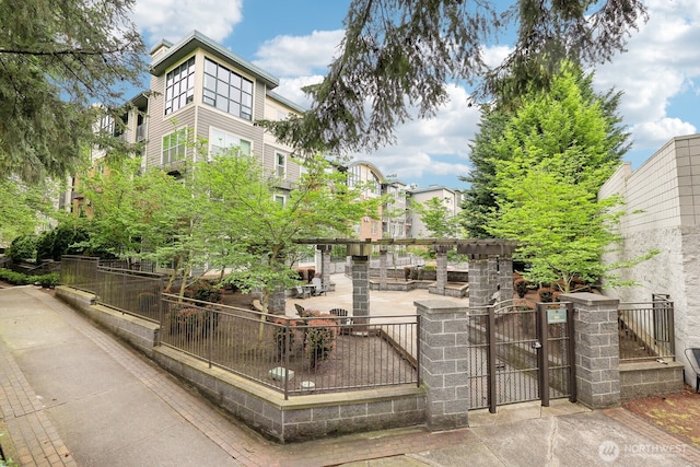 view of community with fence, a gate, and a patio area