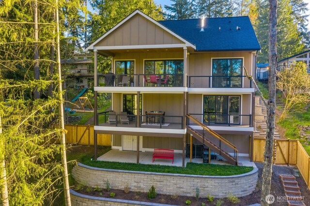rear view of house with roof with shingles, a fenced backyard, a patio area, stairway, and a balcony