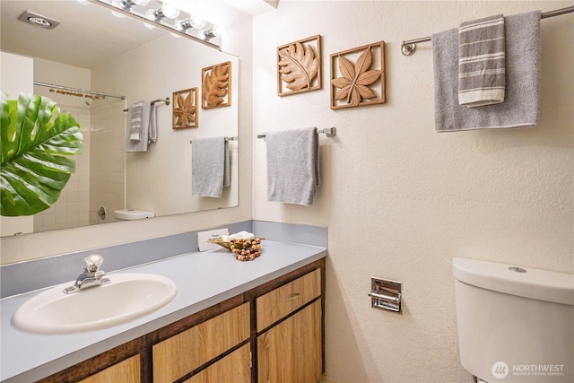 bathroom featuring toilet, walk in shower, and vanity