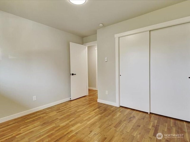 unfurnished bedroom with light wood-style flooring, baseboards, and a closet