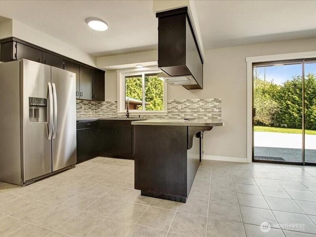 kitchen with a peninsula, stainless steel fridge, extractor fan, backsplash, and light tile patterned floors