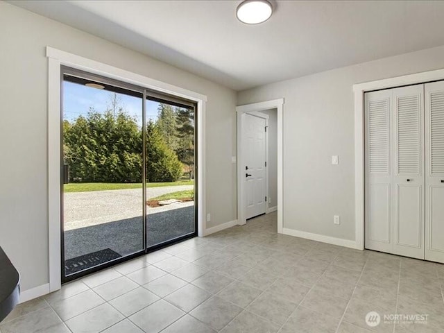 unfurnished bedroom with baseboards, a closet, access to exterior, and light tile patterned floors