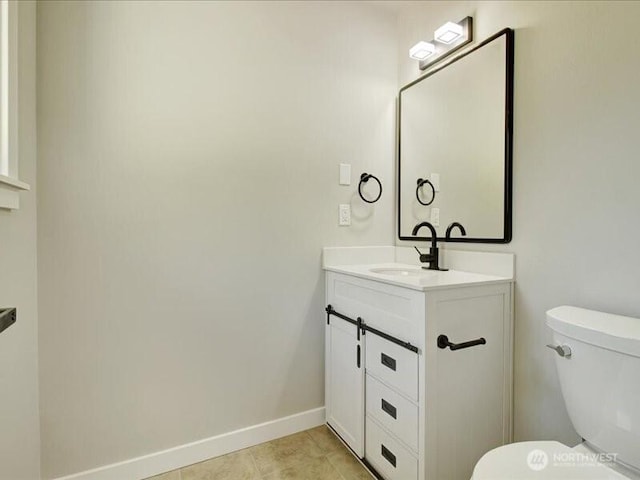 bathroom with toilet, vanity, tile patterned floors, and baseboards