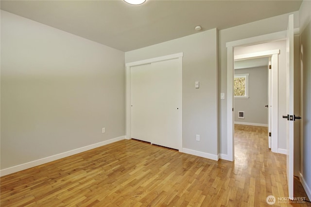unfurnished bedroom featuring baseboards, a closet, and light wood-style flooring