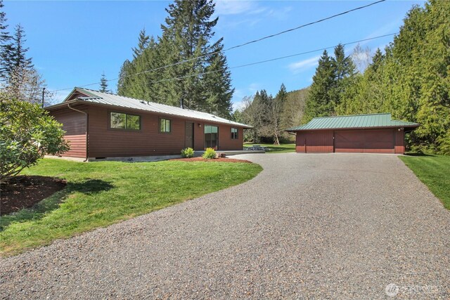 ranch-style home with a detached garage, an outbuilding, a front yard, and metal roof