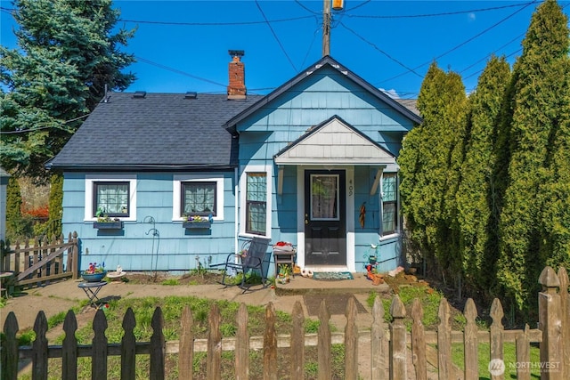 bungalow featuring a chimney, roof with shingles, and fence private yard