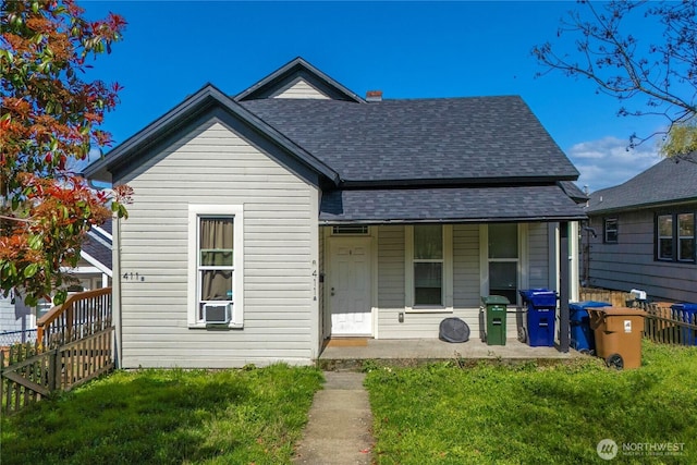 bungalow-style home with fence, a front lawn, and roof with shingles