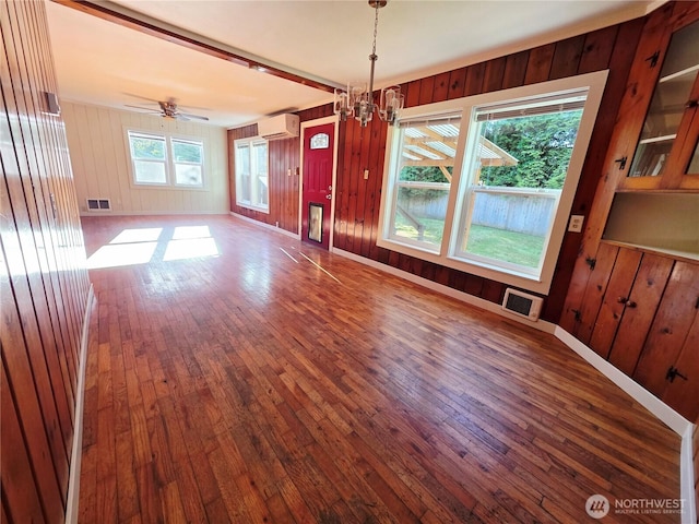 6818 Olympic Hwy, Aberdeen, WA 98520 - unfurnished dining area with visible vents, a chandelier, a wall mounted air conditioner, wooden walls, and wood-type flooring