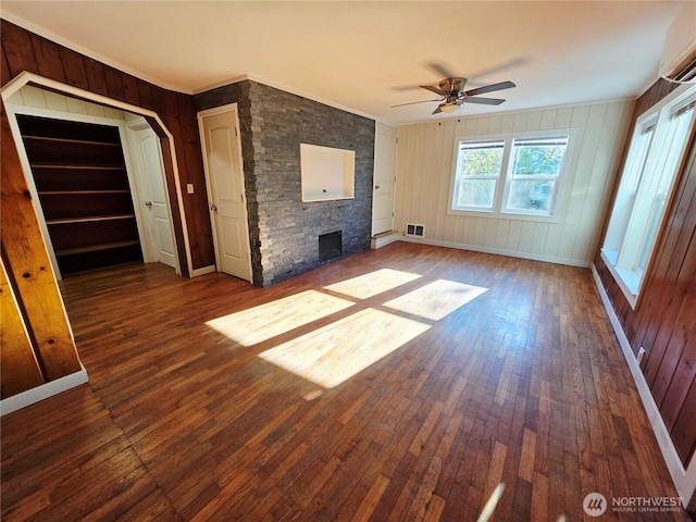 6818 Olympic Hwy, Aberdeen, WA 98520 - unfurnished living room featuring a stone fireplace, visible vents, ornamental molding, wood-type flooring, and ceiling fan
