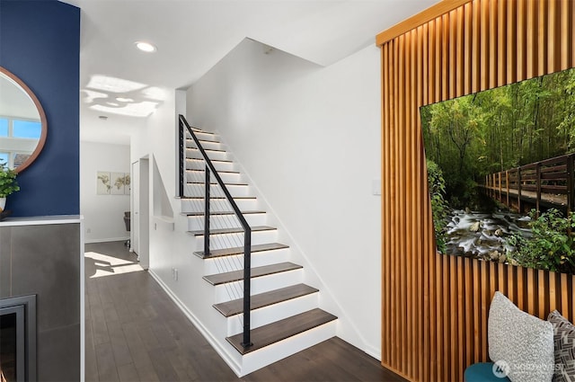 staircase featuring baseboards, wood finished floors, and recessed lighting
