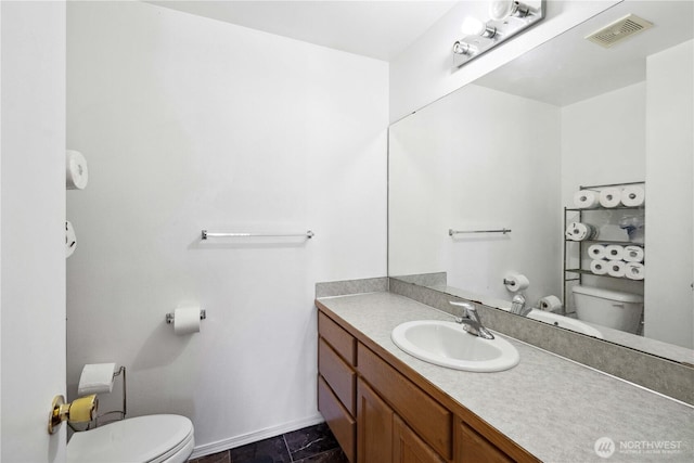 bathroom featuring visible vents, baseboards, vanity, and toilet