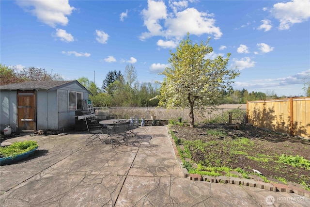 view of patio with a fenced backyard, an outdoor structure, and outdoor dining space