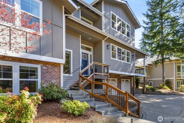 exterior space featuring brick siding, driveway, board and batten siding, and a garage