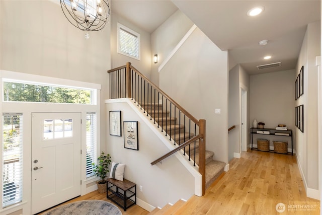 foyer with visible vents, light wood finished floors, stairs, and a high ceiling