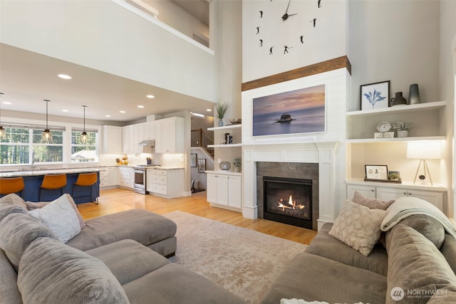 living room with light wood-type flooring, a tiled fireplace, and recessed lighting