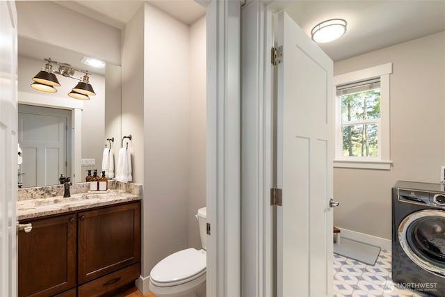 half bathroom with washer / dryer, baseboards, toilet, and vanity