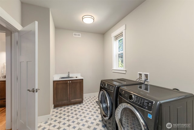 clothes washing area with light floors, visible vents, a sink, washing machine and clothes dryer, and baseboards