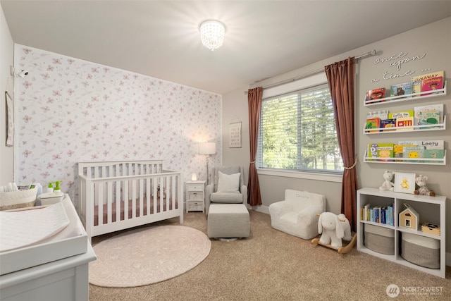 carpeted bedroom featuring wallpapered walls and a crib